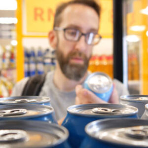 A male buyer examines a can of an alcoholic drink from a ftore fridge